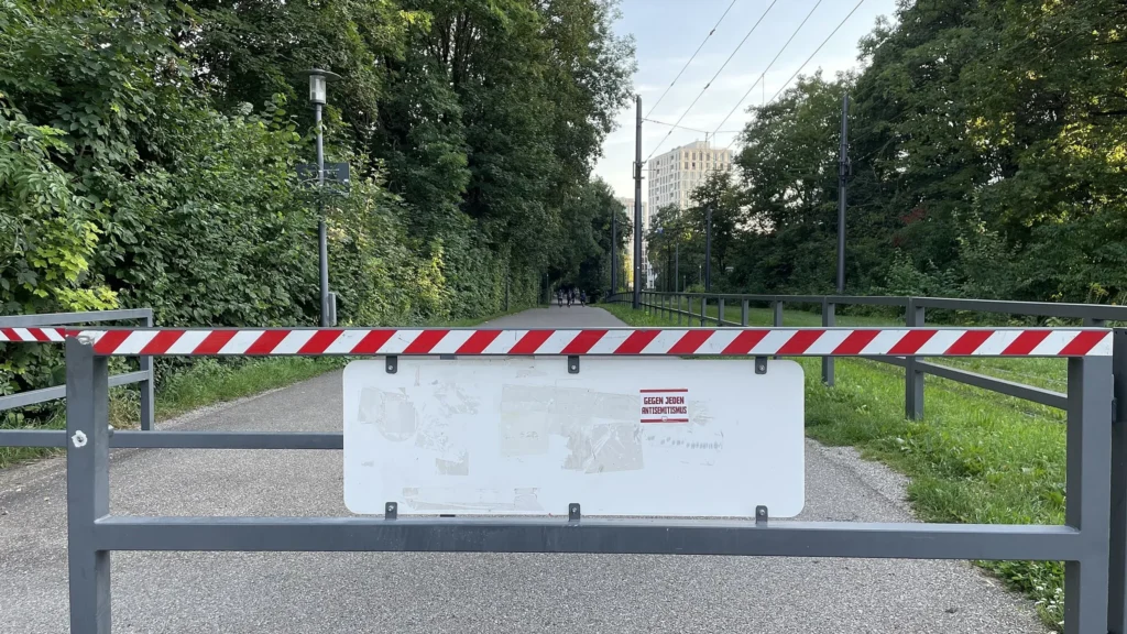 Eine geschlossene Schranke auf einem Weg. Darauf ein Sticker mit der Aufschrift: Gegen jeden Antisemitismus