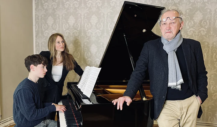 Lesung Rupert Neudeck - 2 Sprecher:innen auf der Bühne mit einem Jugendlichen am Klavier